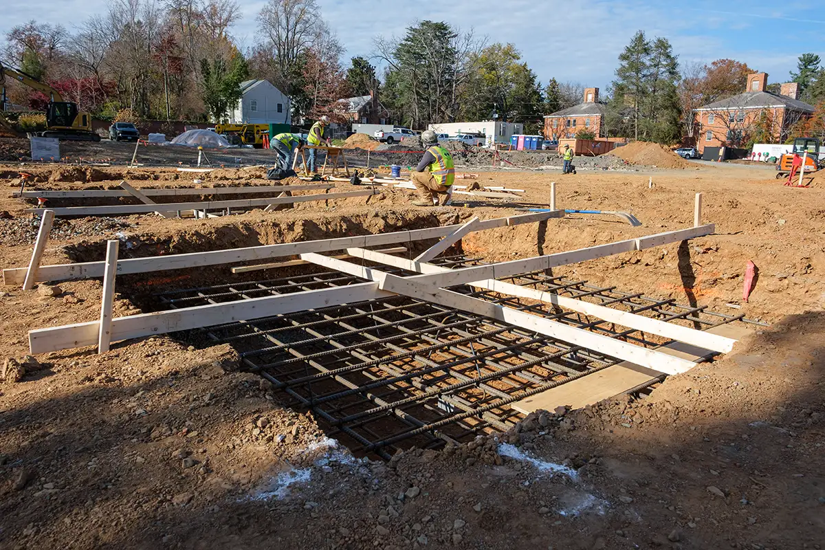 Workers prepare concrete forms for the foundation of the new Aggarwal Hall