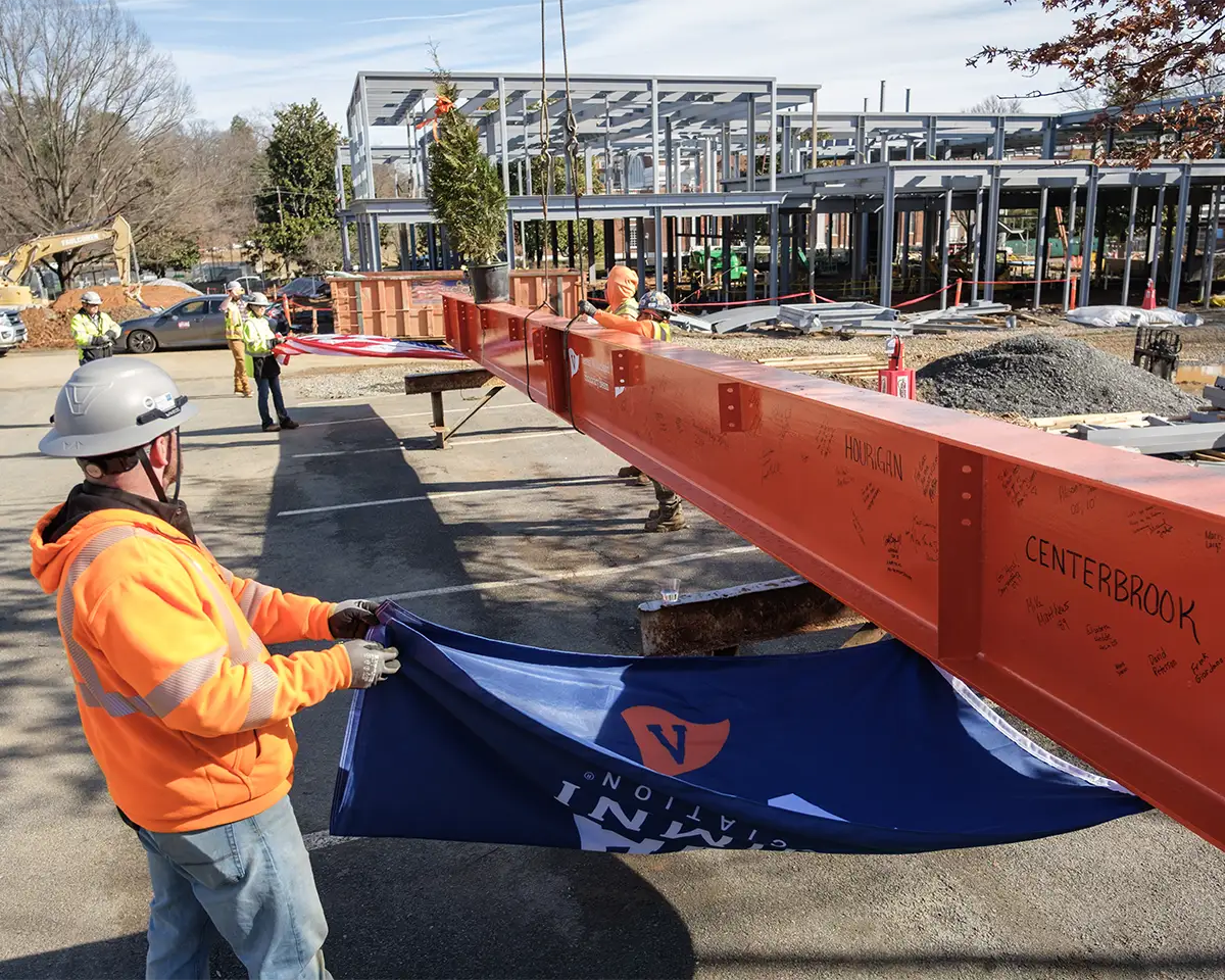 With US and Alumni Association flags attached, the topping out beam is prepared to be lifted into place