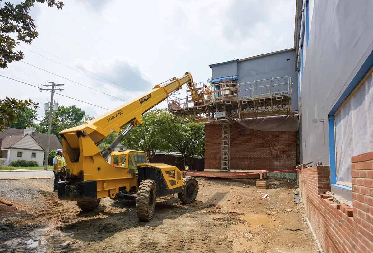 Workers placing brick on the outside of Aggarwal Hall along Lewis Mountain Road