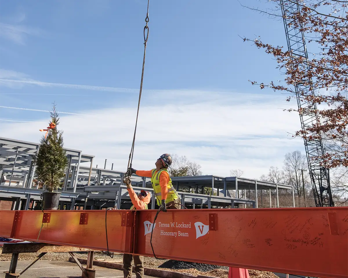 Construction workers strapping up the beam to the crane in preparation for hoisting.