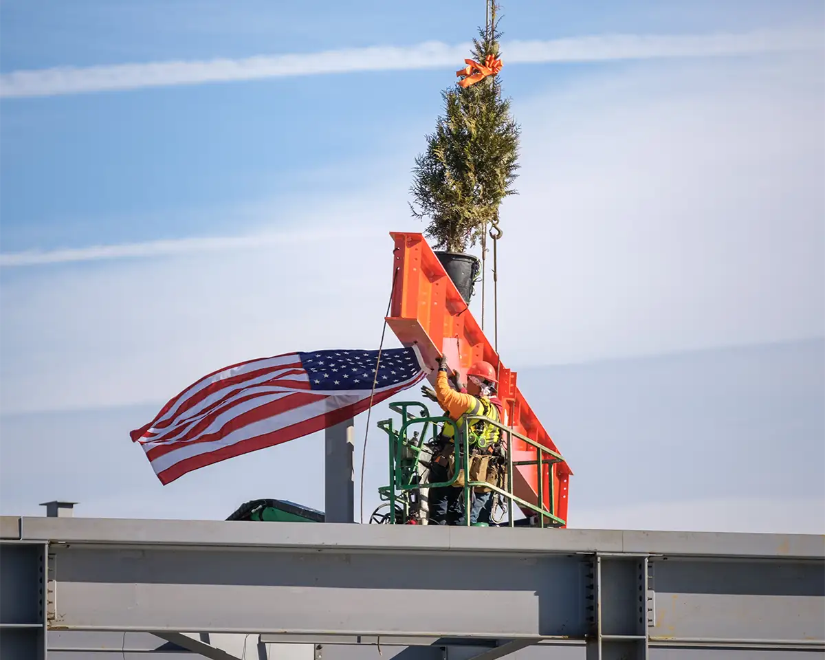 The Teresa W. Lockard Honorary Beam is settled into place atop the new Aggarwal Hall.